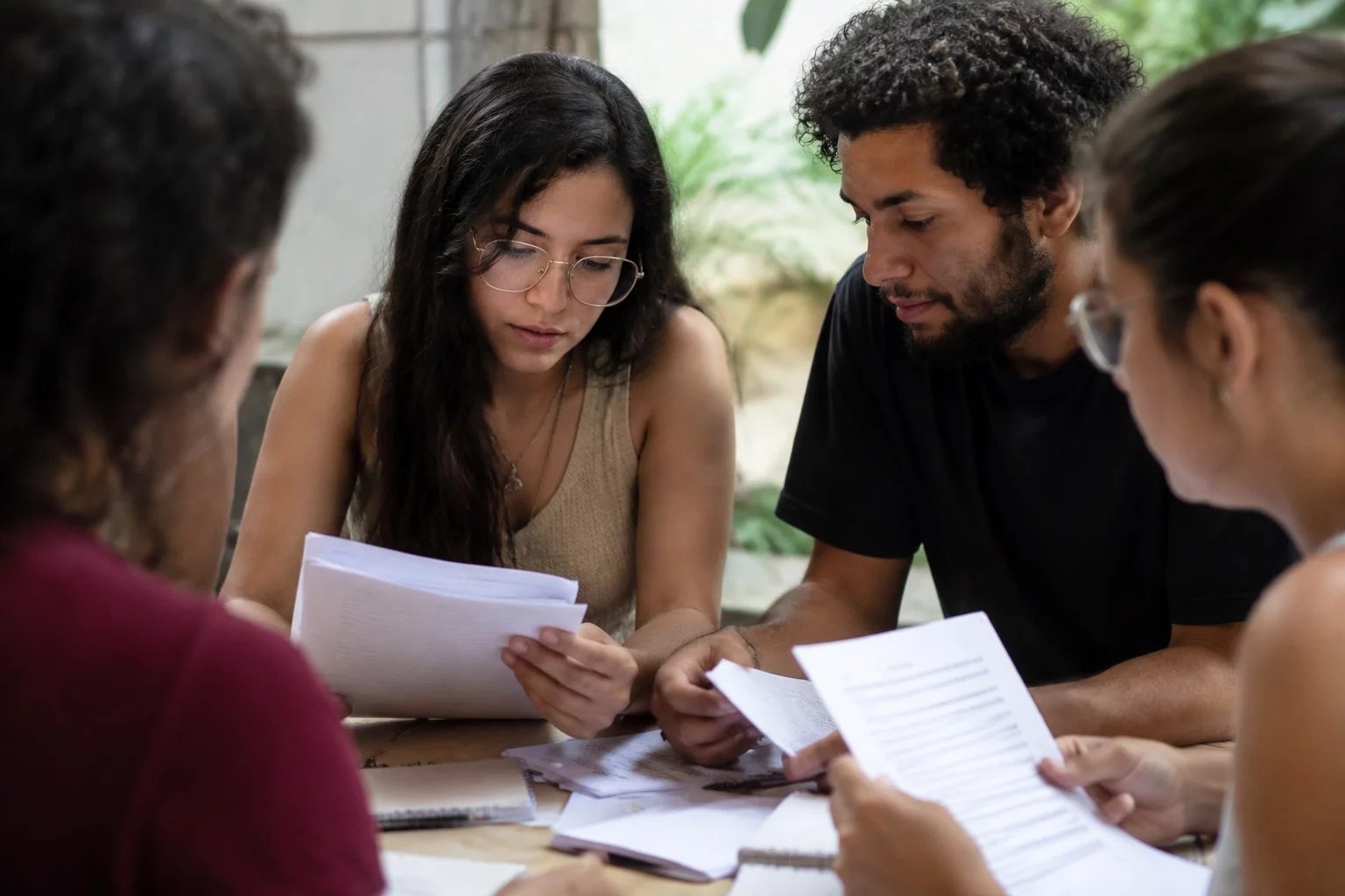 Grupo pequeno lendo páginas impressas de argumentos ao redor de uma mesa